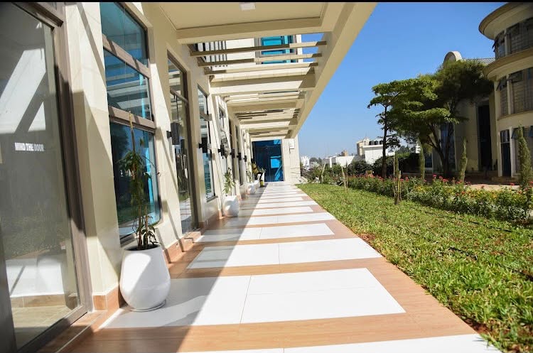 Modern covered walkway with glass storefronts and landscaped gardens at Tsavo and Imperial